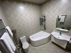 a bathroom with a sink and a toilet and a mirror at Voyah Hotel in Tashkent