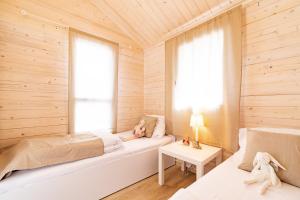 two beds in a room with wooden walls and windows at Marina Holiday in Ustka