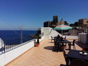 - un balcon avec des tables, un parasol et l'océan dans l'établissement Lipari Centro Storico Flat 7 min from port, à Lipari
