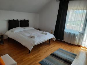 - une chambre avec un lit blanc et une grande fenêtre dans l'établissement Pensiunea Simona, à Sîmbăta de Sus