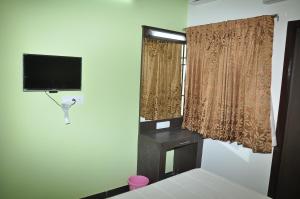 a room with a tv and a window and a bed at Jeyam Residency, Kumbakonam in Kumbakonam