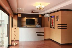 a man standing at a bar in a hotel lobby at Jeyam Residency, Kumbakonam in Kumbakonam