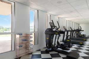 a gym with treadmills and ellipticals in a room with windows at Hôtel Omnubo Collection in Les Épesses
