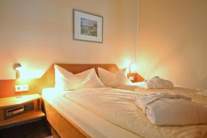 Bett mit weißer Bettwäsche und Kissen in einem Zimmer in der Unterkunft Inselresidenz Strandburg Juist - Wohnung 106 (Ref. 50958) in Juist