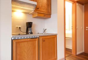 eine kleine Küche mit Holzschränken und einem Waschbecken in der Unterkunft Inselresidenz Strandburg Juist - Wohnung 106 (Ref. 50958) in Juist