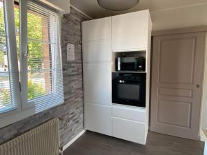 een keuken met een witte kast en een magnetron bij L ETOILE DE MALO in Duinkerke