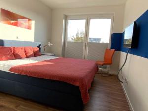 um quarto com uma cama com um cobertor vermelho e uma televisão em Quartier Hohe Geest 8 - a69853 em Cuxhaven