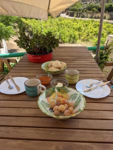 a wooden table with plates and bowls of food on it at Cala Vinagra House in Carloforte