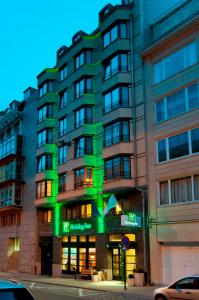 Un bâtiment avec des lumières vertes sur son côté dans l'établissement Holiday Inn Brussels Schuman, an IHG Hotel, à Bruxelles