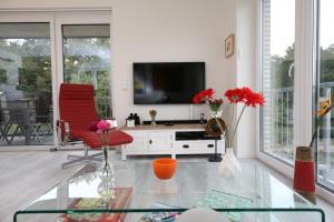 ein Wohnzimmer mit einem TV und roten Stühlen in der Unterkunft Quartier Hohe Geest 15 - Nordseebrise - a69852 in Cuxhaven