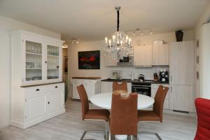 een keuken met witte kasten en een tafel en stoelen bij Quartier Hohe Geest 15 - Nordseebrise - a69852 in Cuxhaven