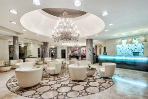 a large lobby with white chairs and a chandelier at AX The Palace in Sliema