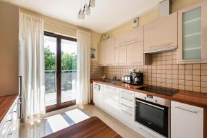 uma cozinha com armários brancos e uma grande janela em Green District Apartment em Varsóvia