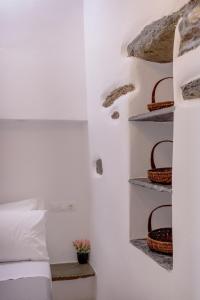 a bedroom with a bed and baskets on the wall at Volta Kalloni - Kalloni village Tinos in Kalloni Tinou