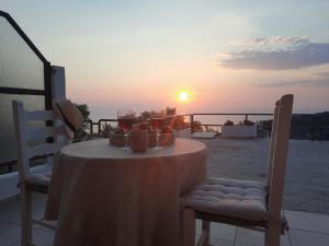 een tafel en stoelen met de zonsondergang op de achtergrond bij Noemie Studios in Athanion