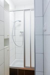a white bathroom with a shower with a glass door at Landhaus Nordsee-Peerhuus in Friedrichskoog
