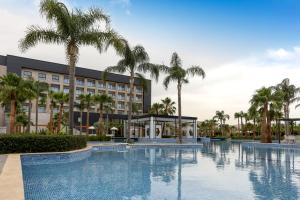 a large swimming pool with palm trees in front of a hotel at Oriental Palace by Agora Complex in Taza
