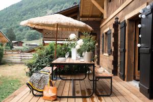 una terraza de madera con mesa y sombrilla en Le Petit Chalet de Montriond en Montriond