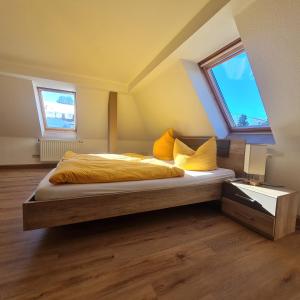 1 Schlafzimmer mit einem Bett mit gelber Bettwäsche und 2 Fenstern in der Unterkunft Wurzelrudis Hostel in Eibenstock
