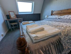 a bedroom with a bed with towels on it at Coach House Cottage in Runswick
