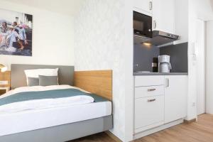 een kleine slaapkamer met een bed en een keuken bij NINO-Boardinghouse 9 - a69890 in Nordhorn