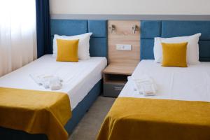 zwei Betten in einem Zimmer mit gelben und blauen in der Unterkunft SPS Hotel in Plowdiw + 54 Fotos