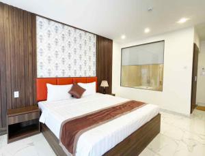 um quarto com uma cama grande e uma cabeceira laranja em Marina Hotel Bình Dương em Thu Dau Mot