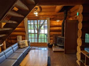 sala de estar con sofá y chimenea en White Tree Log House Madarao Tangram, en Shinano