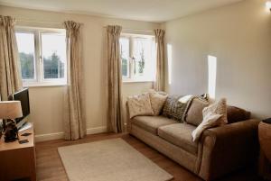 a living room with a couch and two windows at Lake House Annexe - beautiful countryside retreat in Bristol