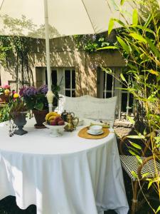 una mesa blanca con un bol de fruta en ella en La Maison des Roses en Moulins