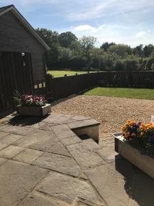 a patio with two benches and flowers in a yard at Lake House Annexe - beautiful countryside retreat in Bristol