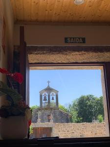 a window view of a church with a tower in the background at Albergue Rectoral San Mamede da Pena EXCLUSIVE FOR PILGRIMS in Negreira
