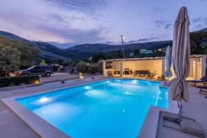 a swimming pool with an umbrella and a house at Melki for 12 people with private pool in Klis +131 photos