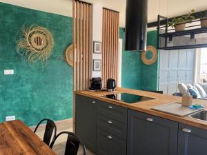 a kitchen with green walls and a table with chairs at SunPola Penthouse in Santa Pola