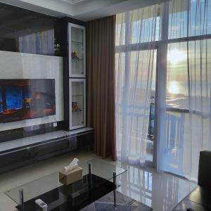 a living room with a tv and a large window at SLEPTOPIA at Formosa Residence - New Best Cozy Place in Town in Nagoya
