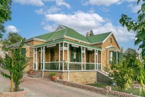 uma grande casa de tijolos com um telhado verde em Ravenscliff Self Catering em Oudtshoorn