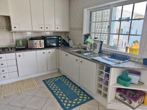 a kitchen with white cabinets and a sink and a window at Vagueira Guest House in Aveiro