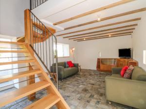 a living room with two couches and a staircase at The Barn at Chatsworth Farm in Leek