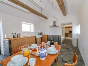 a kitchen with a wooden table with plates and cups at The Barn at Chatsworth Farm in Leek