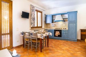 uma cozinha com armários azuis e uma mesa e cadeiras em Trilo Begonia em Marina di Grosseto