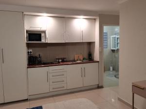 a kitchen with white cabinets and a microwave at Rooikrans Guest House in Johannesburg