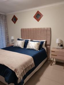 una camera da letto con un grande letto con lenzuola e cuscini blu di Rooikrans Guest House a Johannesburg