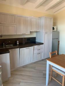 eine Küche mit weißen Schränken und einem Holztisch in der Unterkunft Corte dei Mirti, Appartamento indipendente con ampia veranda in Iglesias