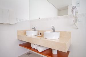 2 lavabos en un baño con paredes blancas en Hotel Chateau, en Campos do Jordão