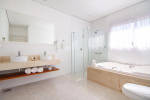 a bathroom with a tub and a toilet and a sink at Hotel Chateau in Campos do Jordão