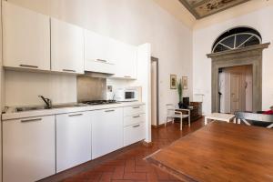 a kitchen with white cabinets and a wooden table at Casa Ghibellina by Mmega in Florence