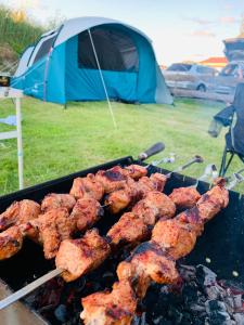 a bunch of food on a grill with a tent at Kempings Vīnkalni in Ventspils