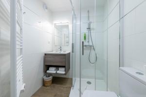 a white bathroom with a shower and a sink at Hotel Le Clos Fleuri in Le Palais