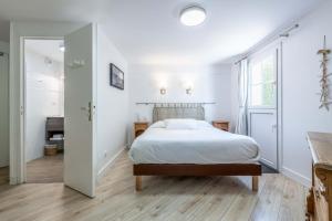 a white bedroom with a bed and a window at Hotel Le Clos Fleuri in Le Palais