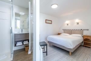 a bedroom with a king sized bed and a bathroom at Hotel Le Clos Fleuri in Le Palais